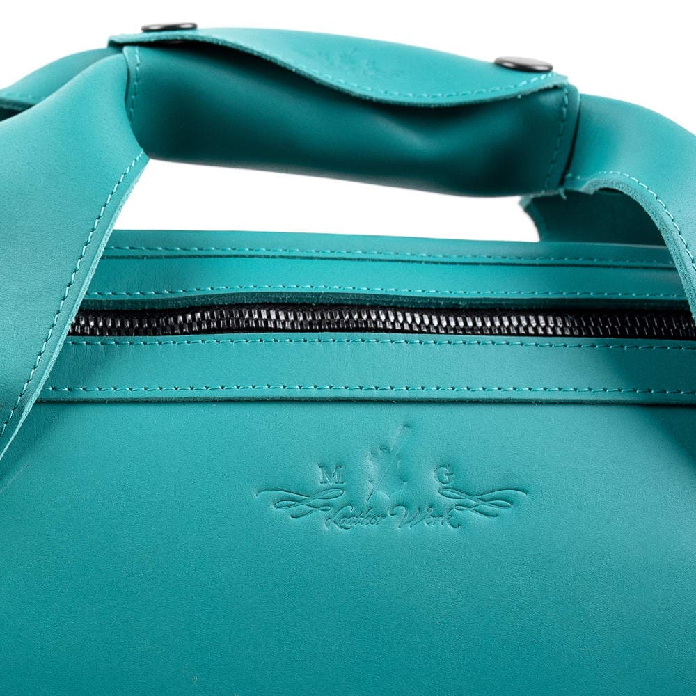 Close-up of Tiffany trumpet case handles with embossed MG Leather Work logo and silver metal hardware
