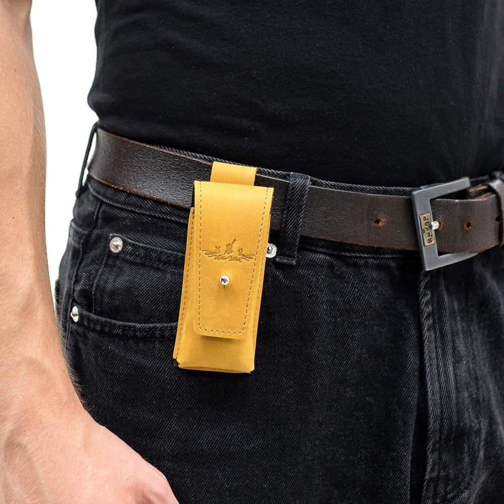Yellow harmonica pouch worn on belt over black jeans with black shirt.