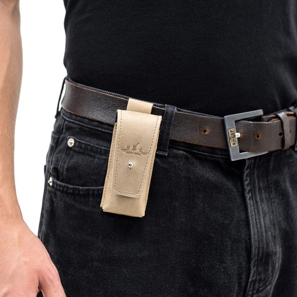 Beige leather harmonica case mounted on brown belt over black jeans