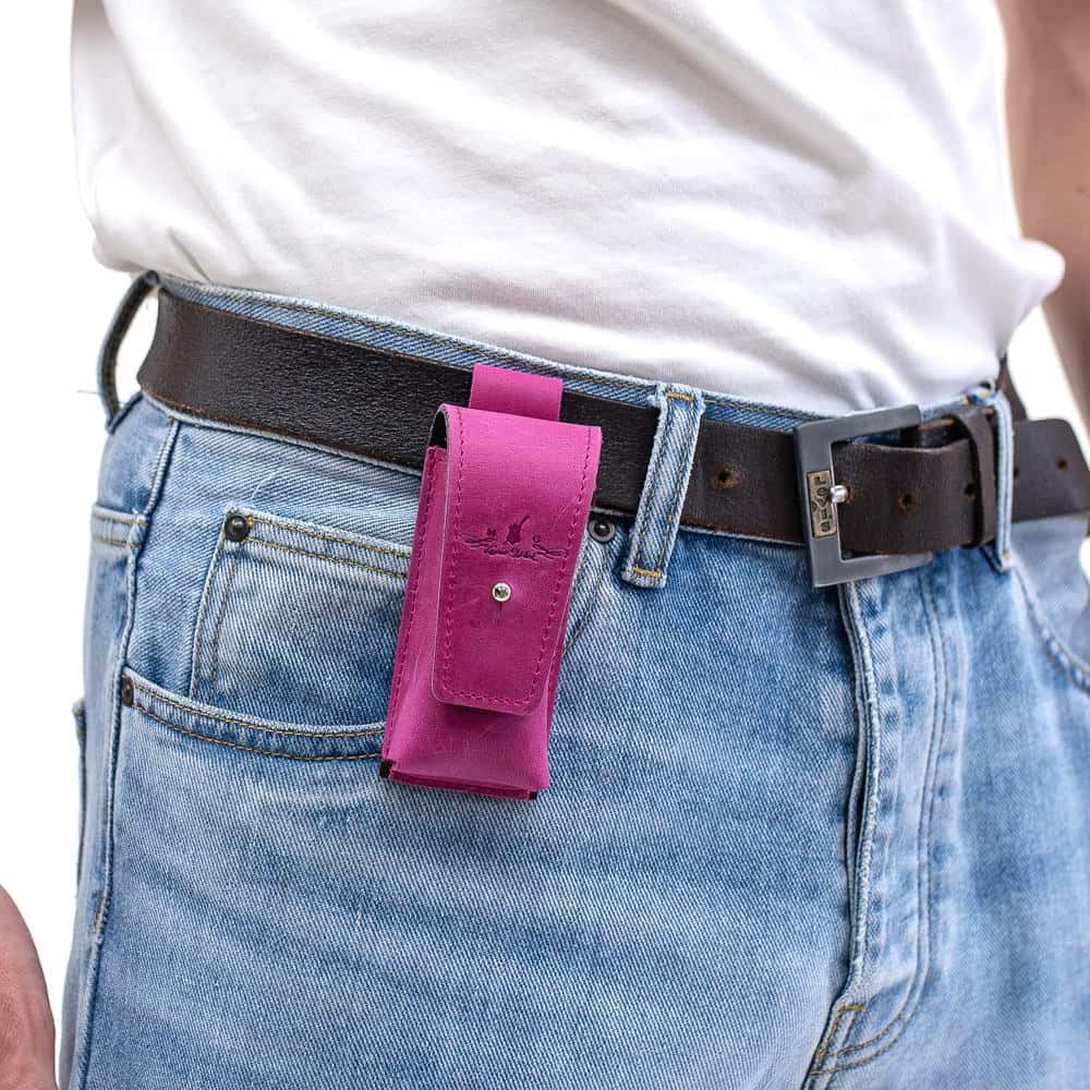 Rose leather harmonica holster attached to black leather belt over blue jeans.