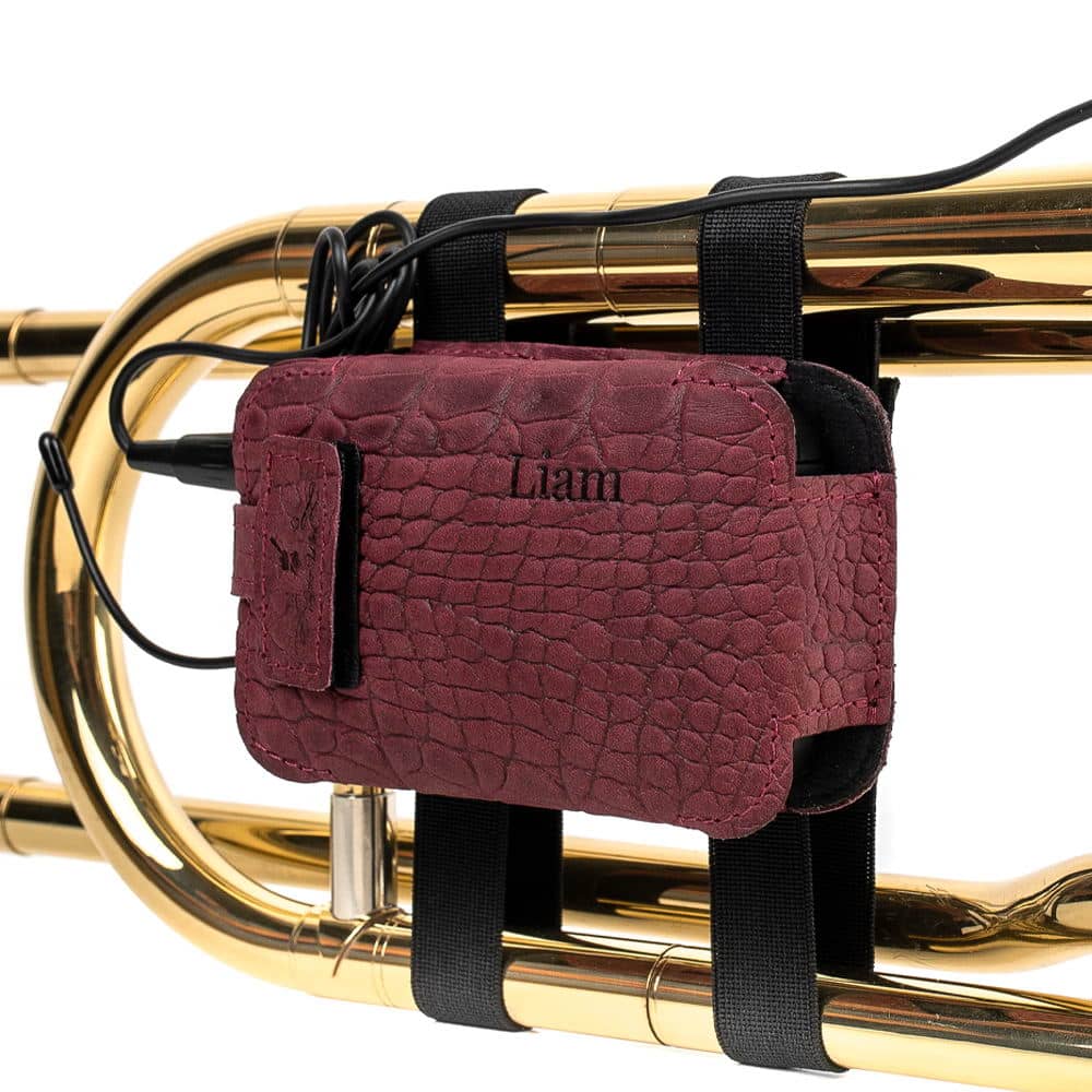 Trombone wireless microphone transmitter pouch in marsala reptile leather — personalized with embossed initials, angled view on trombon