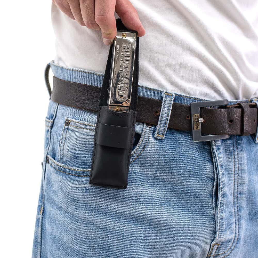 Black harmonica leather pouch on belt as harmonica is pulled out by hand.