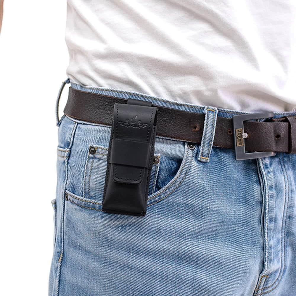 Black leather harmonica case fixed on black belt over denim trousers.