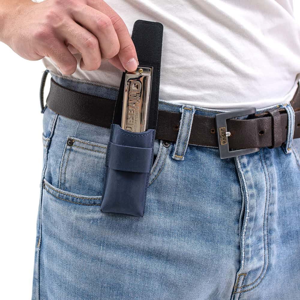 Dark blue harmonica pouch on belt as harmonica is being removed by hand.