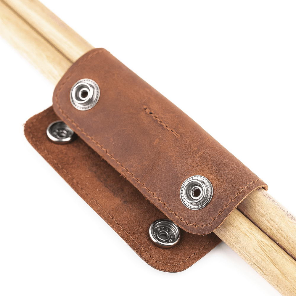 Light Brown leather drumstick holder with metal buttons on a white background