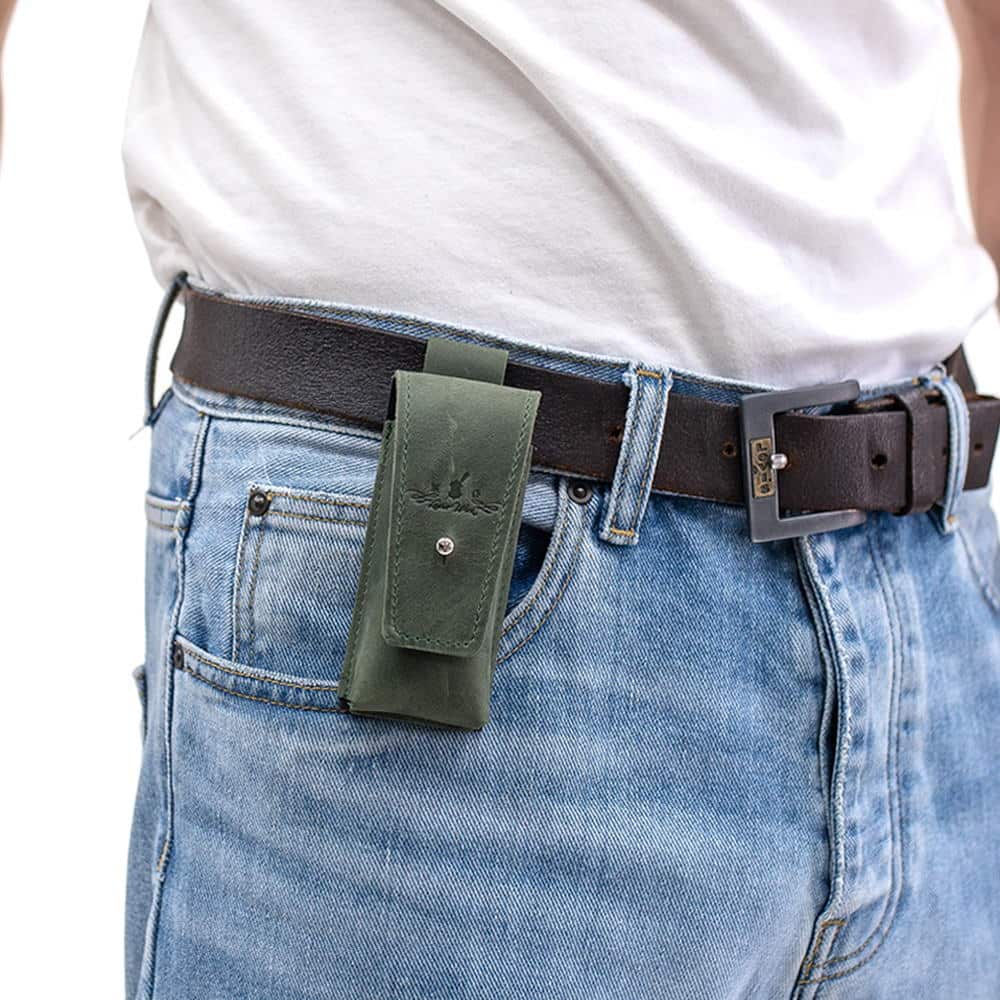Green leather harmonica holster attached to black leather belt over jeans