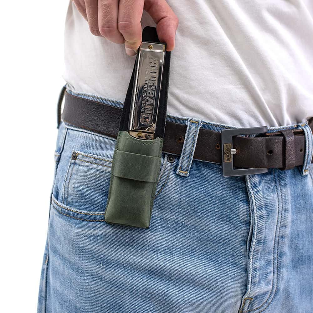 Green harmonica leather pouch on belt with harmonica being removed.