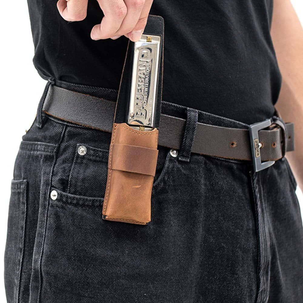 Light brown harmonica pouch on belt while harmonica is being taken out.