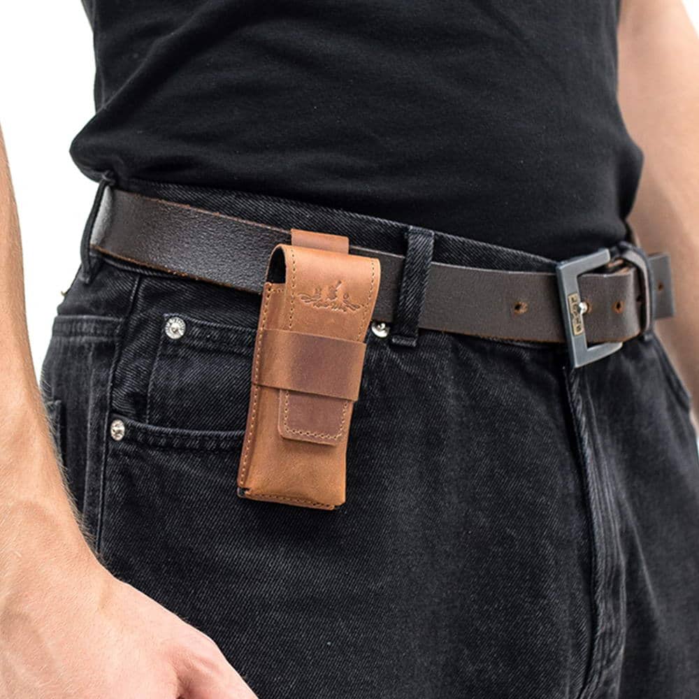 Light brown harmonica leather case attached to black belt on jeans.