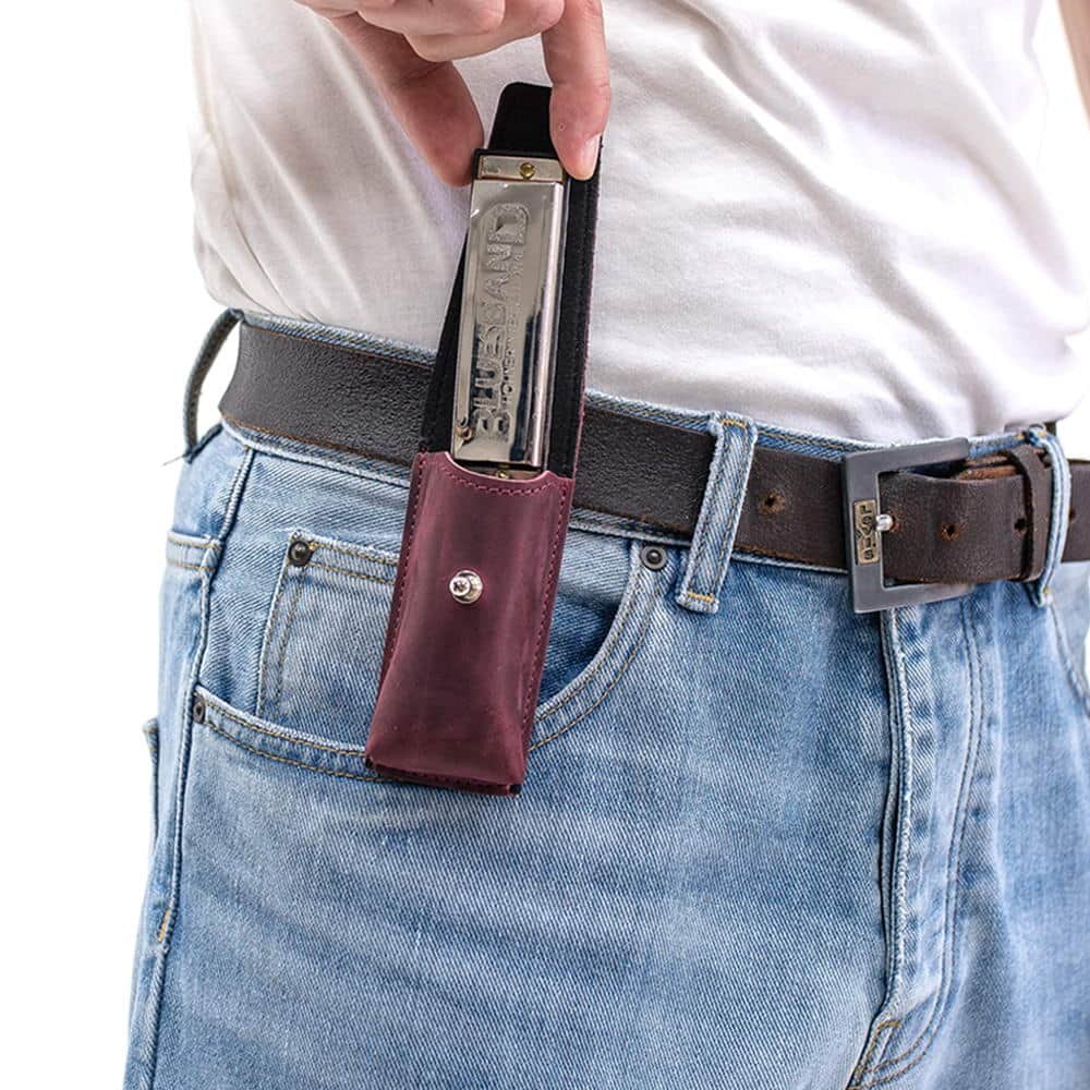 Marsala harmonica leather holder on belt with harmonica being removed by hand.