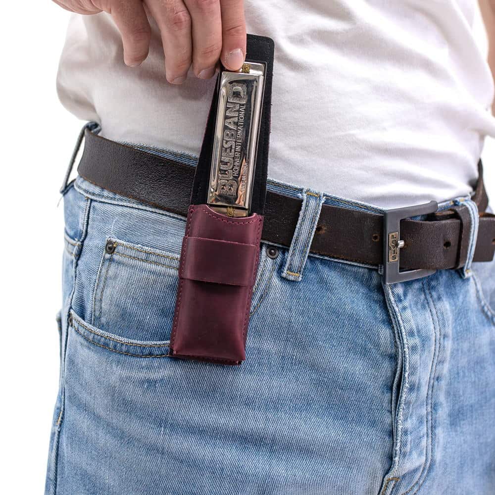 Marsala harmonica leather pouch on belt as harmonica is being taken out.