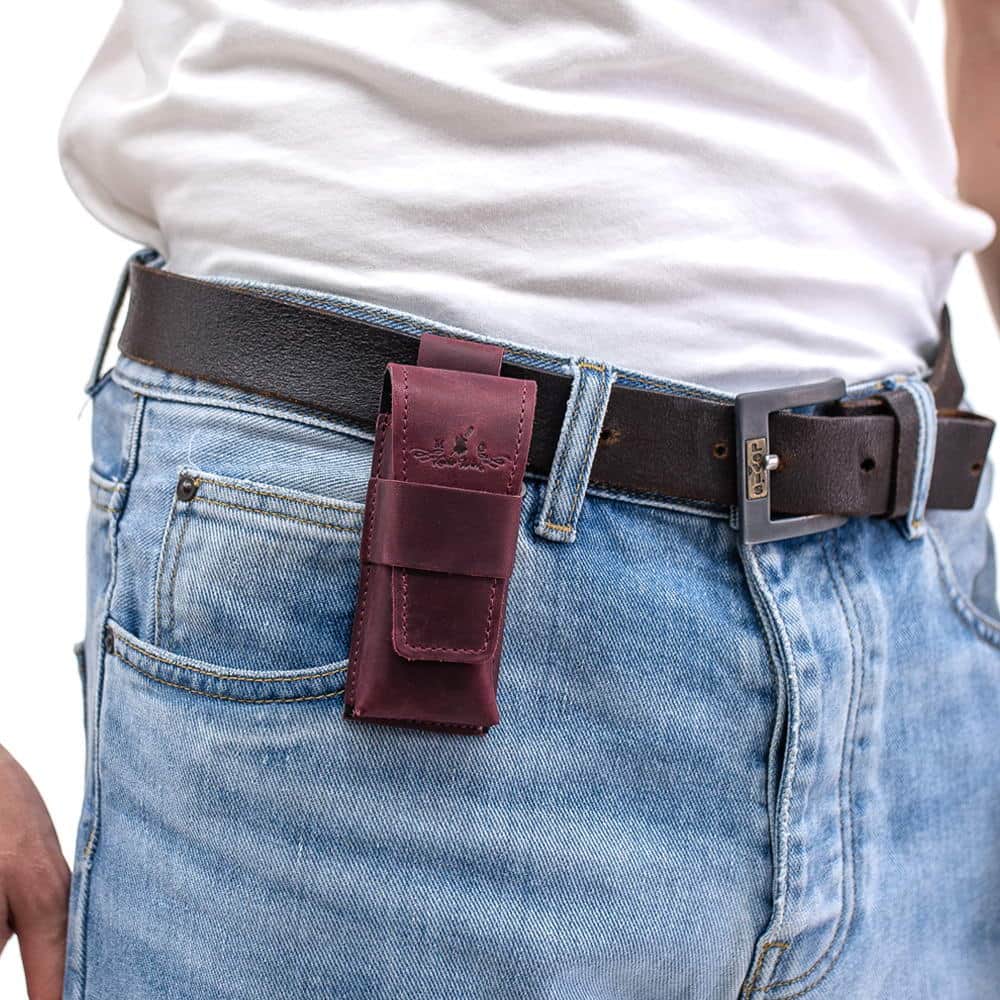 Marsala leather harmonica case mounted on black belt over jeans.