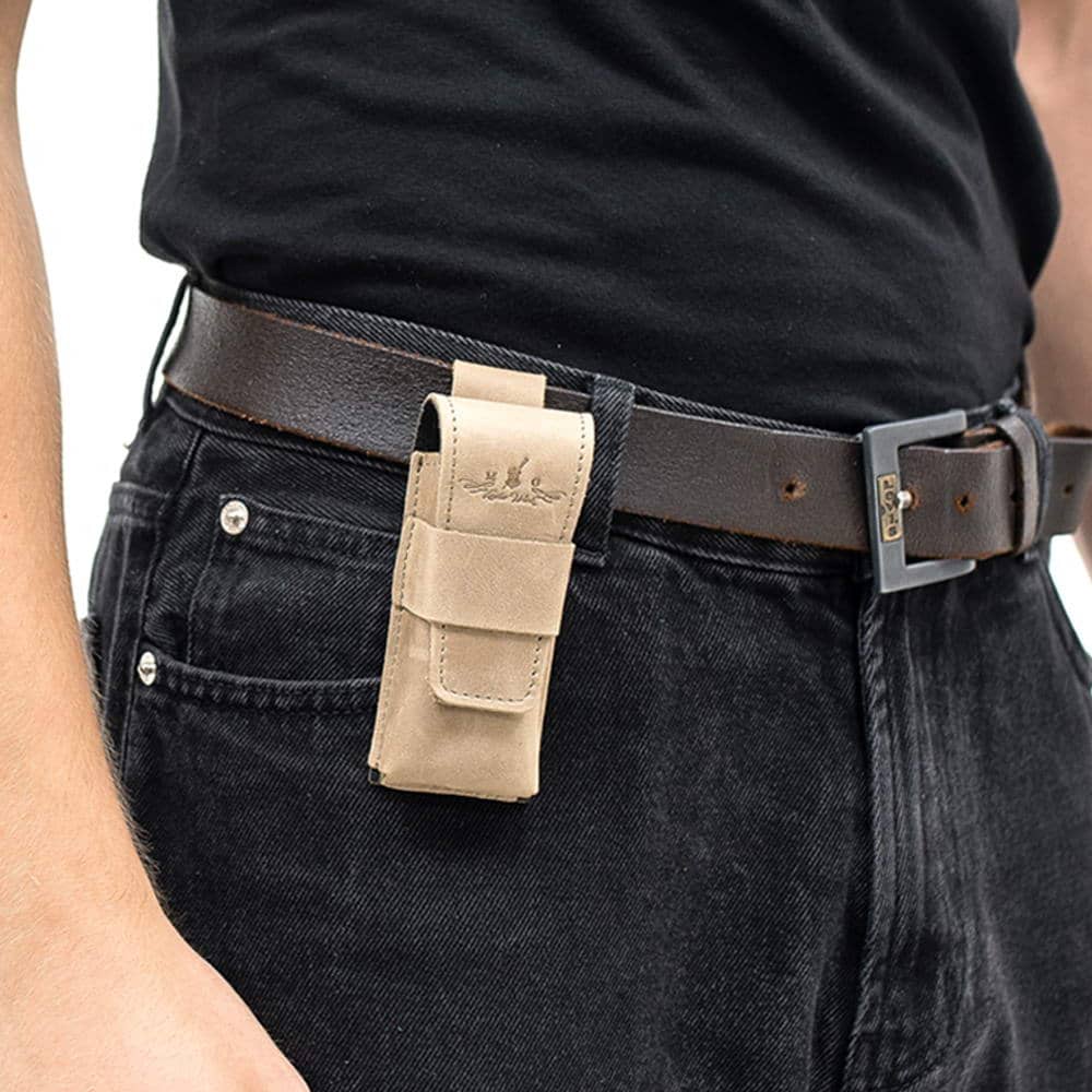 Olive leather harmonica case mounted on black belt over denim jeans.