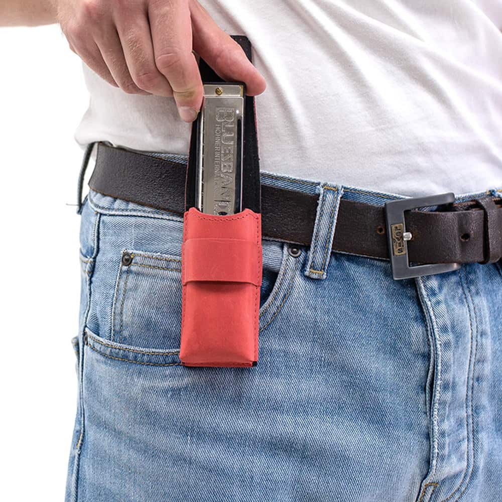 Red harmonica leather pouch on belt as harmonica is being removed.