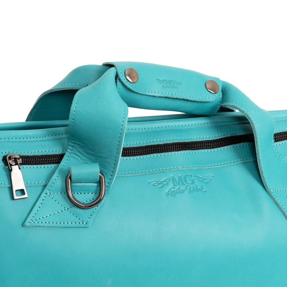 Close-up of Tiffany trumpet case handles with embossed MG Leather Work logo and silver metal hardware
