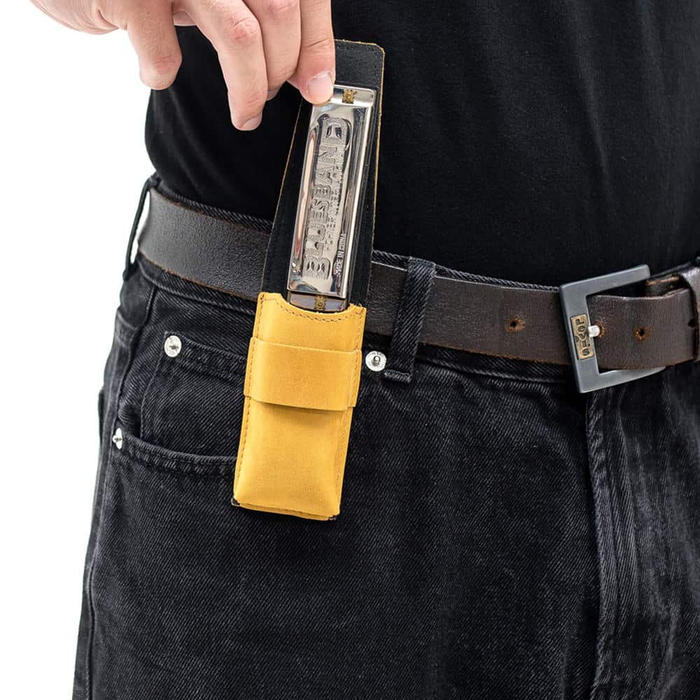 Yellow harmonica leather pouch on belt as harmonica is pulled out.
